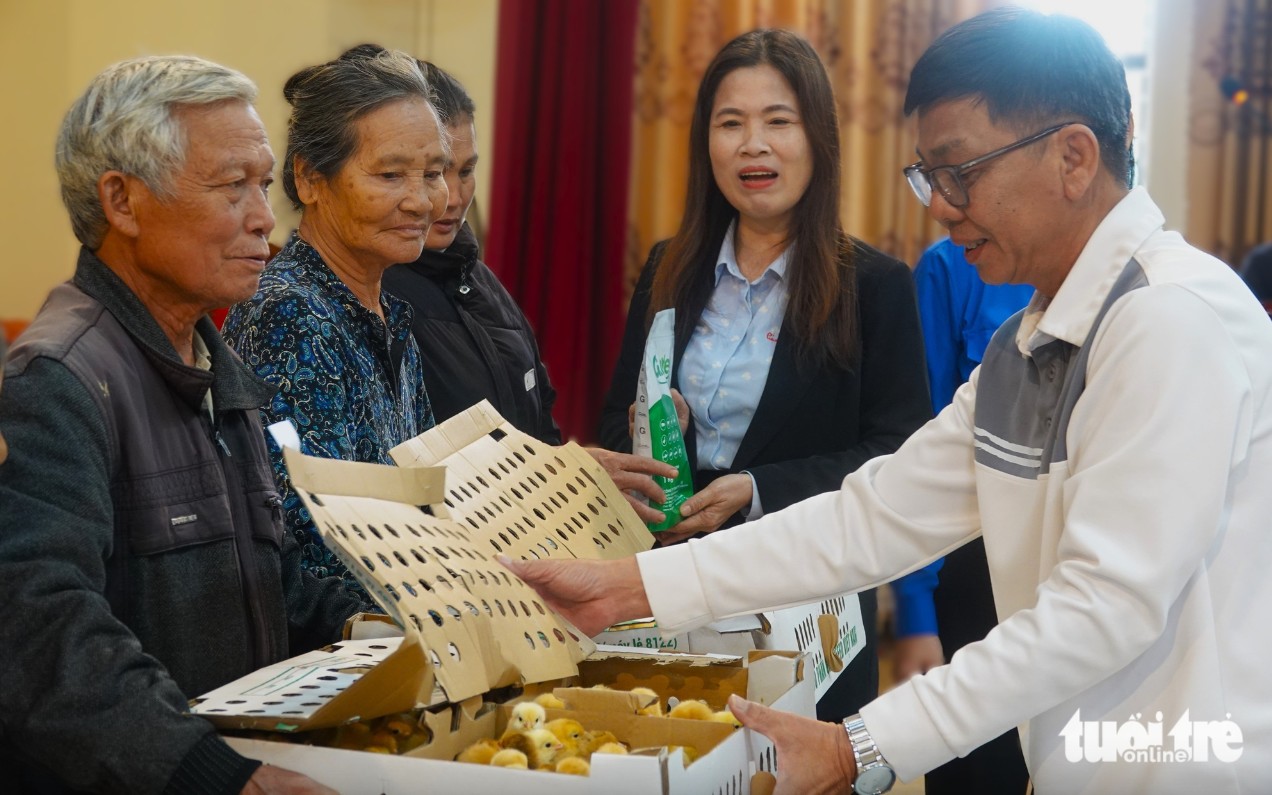 Đại diện báo Tuổi Trẻ và chính quyền địa phương trao gà cho người dân xã Đồng Tiến